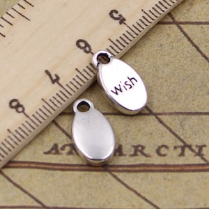May include: Two silver oval-shaped charms. One charm has the word "wish" engraved on it.