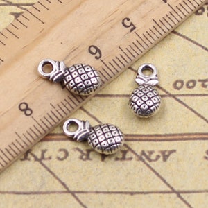 May include: Three silver pineapple charms with a loop at the top for attaching to jewellery or other crafts.