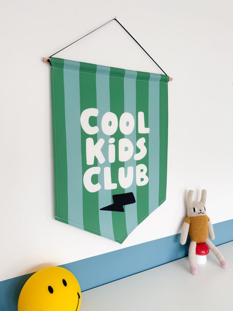 May include: Green and blue striped fabric banner with the text "COOL KIDS CLUB" in white letters and a black lightning bolt.