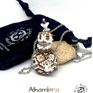 May include: A beaded pendant necklace featuring a small, round, bottle-shaped container covered in brown, white, and gold seed beads. The pendant includes a silver-toned bird charm and a decorative stopper, suspended from a silver-toned chain.
