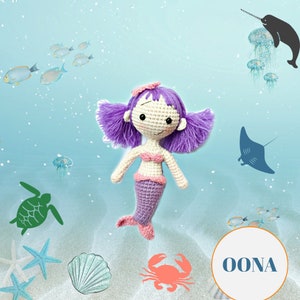 May include: A handmade crochet mermaid doll with purple hair, a pink top, and a purple tail. The doll is set against a blue background with sea-themed illustrations, including fish, a turtle, and a crab. The word "OONA" is in a circle.