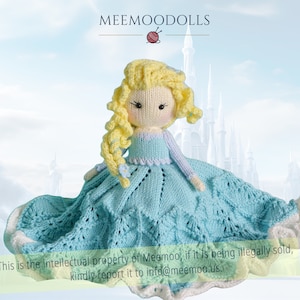 以下が含まれることがあります： 金髪のニット製のドールが、薄い青色のドレスと白い王冠を着用しています。ドールは薄い青色の毛布の上に座っており、白い縁取りが施されています。背景は、ぼやけた城の画像です。