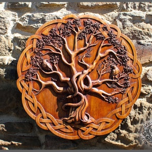 May include: A circular wooden carving depicting a tree with a snake, birds, and a Celtic knot border. The wood is stained a warm brown colour. The carving is mounted on a stone wall. The carving is approximately 40 cm in diameter.