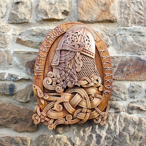 May include: A wooden carving of a Viking warrior's head with a horned helmet, surrounded by intricate knotwork. The carving is mounted on a wall and reads "TIME TO BE STRONG * RAGNAROK *"