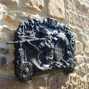 Puede incluir: Una placa de metal negro con una talla detallada de un guerrero que sostiene una lanza y un escudo. La placa est&aacute; montada en una pared de piedra y presenta un escudo de armas con las letras "A" y "S" entrelazadas.