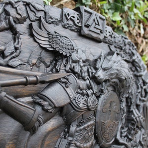 Puede incluir: Una talla de madera oscura de un guerrero con una lanza y un escudo, un lobo y un &aacute;rbol de la vida. La talla es detallada e intrincada, con un acabado de madera oscura.