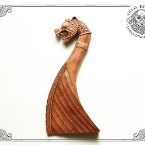 Pode incluir: Uma escultura de madeira de uma proa de navio com cabeça de dragão, com detalhes intrincados e um acabamento marrom avermelhado. A escultura é um design viking tradicional.