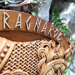 May include: A wooden wall hanging with intricate carvings depicting a Viking warrior and the word "Ragnarok" in runes.