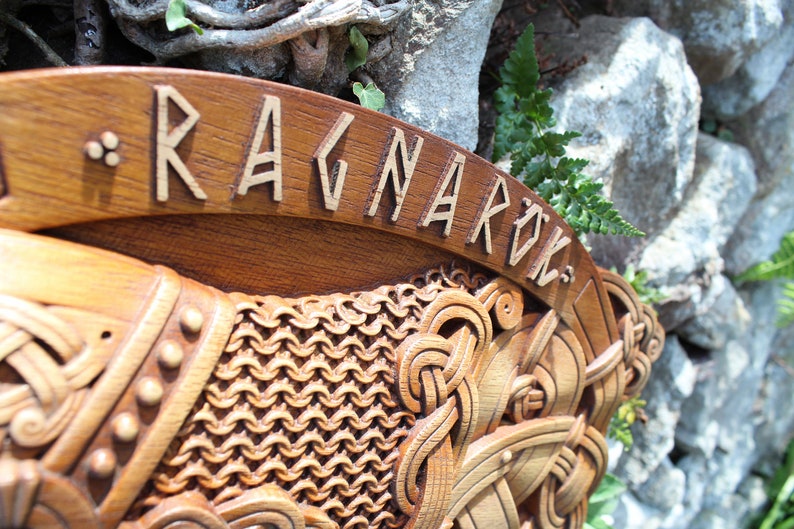 May include: A wooden wall hanging with intricate carvings depicting a Viking warrior and the word "Ragnarok" in runes.