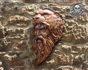 May include: A wooden carving of a bearded man's face with a lion's head on top. The carving is mounted on a stone wall. The artist's name, "Oleg Krogko", is visible in the upper right corner of the image.