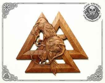May include: A wooden carving of two ravens perched on a branch within a triple triangle symbol, known as the Valknut. The carving is a dark brown color and has a detailed, intricate design.