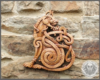 May include: A wooden carving of a wolf in a Celtic knot design. The wolf is brown and has a detailed face. The carving is mounted on a stone wall.