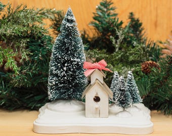 Birdhouse Holiday Scene features a tiny birdhouse and bottlebrush trees fully glued to a handpainted pedestal. Cute on your mantel!