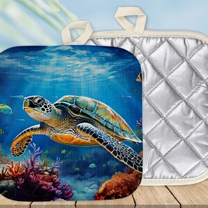 Puede incluir: Un posavasos azul y verde con una tortuga marina nadando en el océano. El posavasos tiene un reverso acolchado.