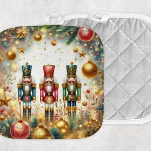 Op de afbeelding: Een vierkante pannenlap met kerstthema met drie speelgoednotenkrakers in rode, blauwe en groene uniformen. Het ontwerp bevat gouden ornamenten, sterren en feestelijk groen. Een aparte, wit gewatteerde pannenlap is zichtbaar.