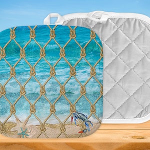 Puede incluir: Salvamanteles cuadrado con diseño de playa. La parte delantera presenta una escena de océano turquesa con una red de cuerda, un cangrejo azul y estrellas de mar. La parte trasera es blanca con un patrón acolchado y un lazo para colgar. Decoración de cocina.