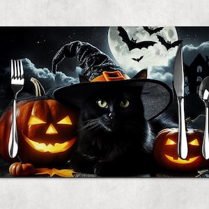 May include: Halloween-themed placemat featuring a black cat wearing a witch hat, flanked by two carved jack-o'-lanterns. A full moon, bats, and a spooky house complete the scene. Silverware is placed on the mat.