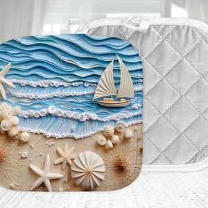 May include: A white quilted hot pad with a blue and white seashell and sailboat design. The design features a sailboat on a blue ocean with white waves and seashells on a sandy beach.