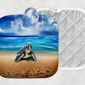 May include: A pair of blue and white pot holders featuring a sea turtle on a beach scene. The pot holders are quilted and have a white border.