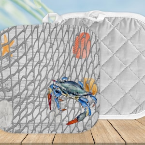 May include: A pair of gray and white quilted pot holders with a nautical theme. One pot holder features a blue crab, starfish, seashells, and a fishing net on a gray wood background. The other pot holder is plain gray with diamond quilting.