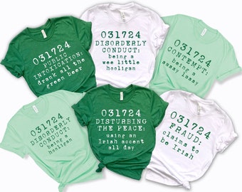 Könnte beinhalten: Sechs grüne und weiße T-Shirts mit einem St. Patrick's Day-Motiv. Die Shirts zeigen den Text "031724" und verschiedene Sätze, die sich auf die irische Kultur beziehen, wie "Öffentliche Trunkenheit", "Unordentliches Verhalten", "Verachtung", "Störung des Friedens" und "Betrug".