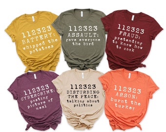 May include: A collection of six short-sleeved t-shirts in various colors, each with a unique humorous text design in white. The texts include phrases like "BATTERY: whipped the potatoes" and "ARSON: burnt the turkey."