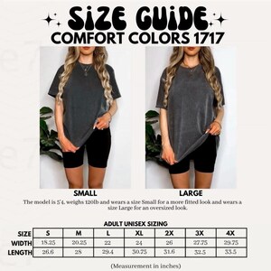 May include: A size guide for Comfort Colors 1717 t-shirts featuring two images of a charcoal grey shirt in size small and large. Includes a sizing chart with width and length measurements in inches for sizes S through 4X, plus model fit details.