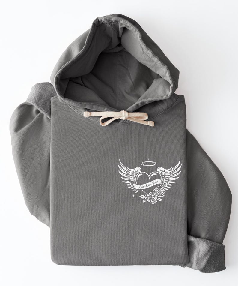 May include: A gray hoodie with a drawstring and a white graphic on the front. The graphic features a heart with wings, a halo, roses, and the text "Loved One Here."
