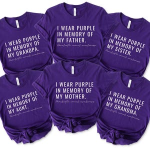 May include: Six purple t-shirts with white text that reads "I wear purple in memory of my [family member]. Pancreatic cancer awareness." The family members listed are grandpa, father, sister, aunt, mother, and grandma.