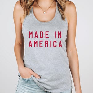 K&ouml;nnte beinhalten: Ein graues Tanktop mit dem Text "MADE IN AMERICA" in Rot.