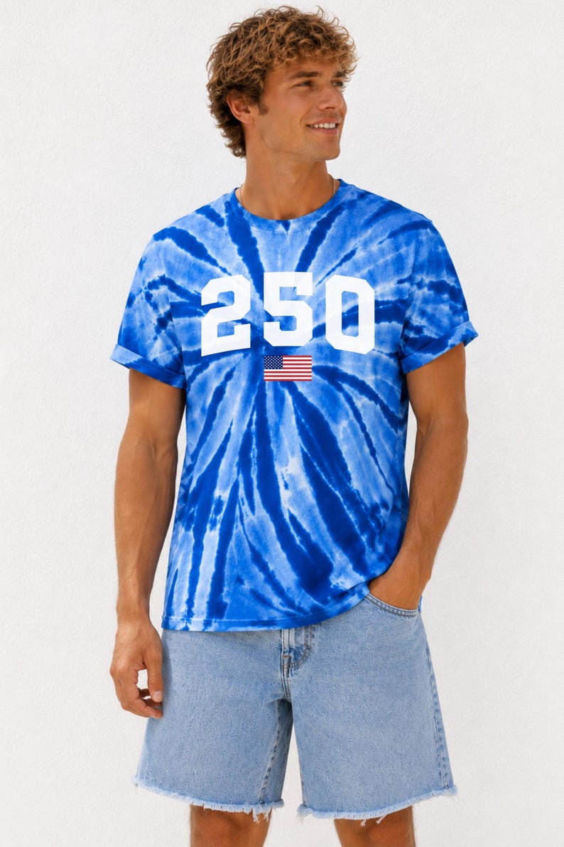 May include: A blue tie-dye t-shirt featuring the number "250" in white, with a small American flag graphic. The shirt is worn with denim shorts. The style is casual and suitable for summer.