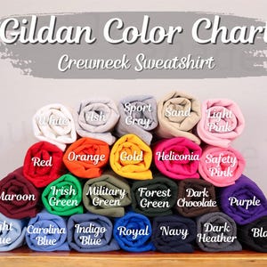 May include: A color chart for Gildan crewneck sweatshirts, displaying a variety of rolled-up fabric samples. Colors include white, ash, sport gray, sand, light pink, red, orange, gold, and more. The text "Gildan Color Chart" is at the top.