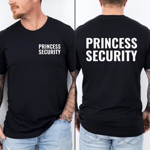 Może przedstawiać: Czarny T-shirt z nadrukiem "Princess Security" w kolorze białym na plecach i tym samym tekstem w mniejszej czcionce z przodu.