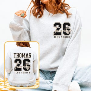 May include: Light gray sweatshirt with the number "26" and the word "Twenty" in a script font. The text "ICHS SENIOR" is below. The back of the sweatshirt has the name "THOMAS" above the number "26" and the word "Twenty" and "ICHS SENIOR".