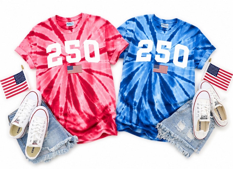 May include: Two tie-dye t-shirts, one red and one blue, each with the number "250" in white and an American flag patch. White trainers and denim shorts are paired with each shirt. American flags are placed on the sides.