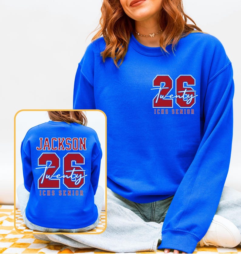 May include: A royal blue sweatshirt with the number "26" and the word "Twenty" in a red and white design. The text "ICHS Senior" is below the number. The back of the sweatshirt also features the name "Jackson" and the number "26".