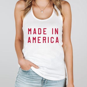 K&ouml;nnte beinhalten: Ein wei&szlig;es Tanktop mit dem Text "MADE IN AMERICA" in Rot.
