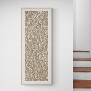 Puede incluir: Una impresión de arte abstracto enmarcada con un patrón beige y blanco. La impresión está en un marco de madera claro y delgado.