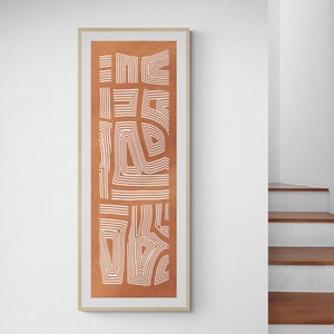 May include: A framed abstract print with a white geometric design on a burnt orange background.