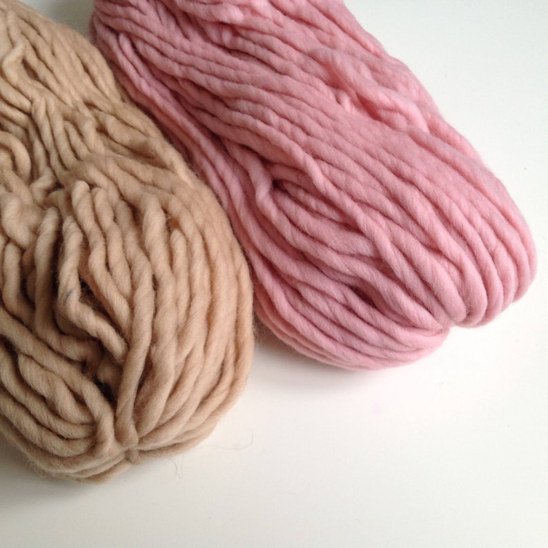 May include: Two skeins of yarn, one in a light brown color and the other in a light pink color.
