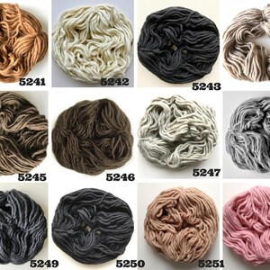 May include: Twelve skeins of yarn in various colors, including brown, beige, black, gray, and pink. Each skein is arranged in a circle and labeled with a number.