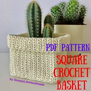 May include: A crocheted square basket in a cream color with the text "PDF PATTERN SQUARE CROCHET BASKET" in red and blue. The basket is filled with two green cactus plants.