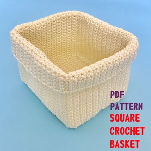 May include: A white crocheted square basket. The basket is made with a simple stitch and has a clean, modern look. PDF PATTERN SQUARE CROCHET BASKET.