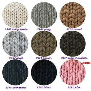 May include: A color chart of yarn samples in various colors, including ivory white, gray, camel, beige, brown, dark chocolate, anthracite, black, and pink. The yarn is chunky and has a knitted texture.