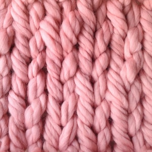 May include: Close-up of a pink knitted fabric with a chunky cable knit pattern.