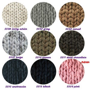 Op de afbeelding: Een kleurenkaart met garenstalen in verschillende kleuren, waaronder ivoorwit, grijs, camel, beige, bruin, donkerbruin, antraciet, zwart en roze. Het garen heeft een dikke breistructuur.