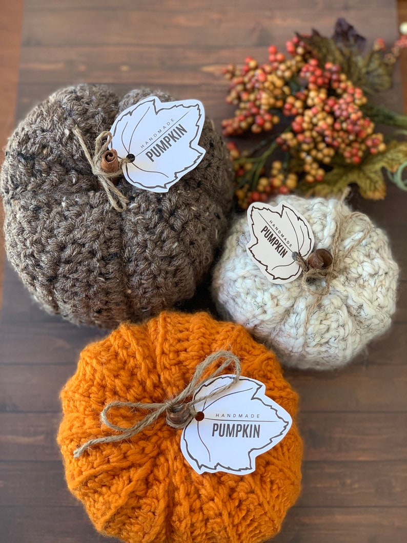 Puede incluir: Tres calabazas de crochet en marr&oacute;n, blanco y naranja con etiquetas en forma de hoja que dicen "Handmade Pumpkin".