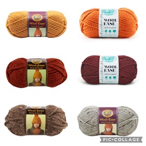 Puede incluir: Seis ovillos de lana Lion Brand Wool-Ease Thick & Quick en varios colores oto&ntilde;ales: amarillo mostaza, naranja, burdeos, marr&oacute;n y gris. Cada ovillo tiene una etiqueta con el nombre de la marca y el peso del hilo.