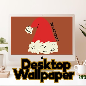 Può includere: Un monitor di computer mostra un design di cappello di Babbo Natale rosso con il testo "Mrs. Travers" su sfondo marrone. Le parole "Desktop Wallpaper" sono in nero con contorno dorato. Sono visibili anche una pianta, occhiali e una tazza.