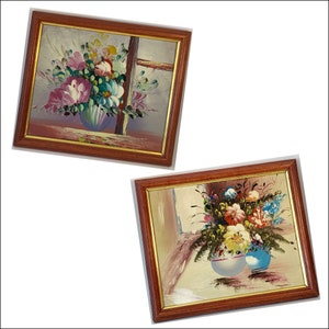 May include: Two framed paintings with floral arrangements in vases. The top painting features a bouquet of pink, purple, and blue flowers in a blue and white vase. The bottom painting features a bouquet of red, yellow, and blue flowers in a white vase and a blue vase.
